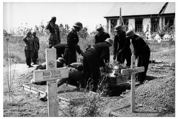 Burial of an officer in a coffin by a Wehrmacht chaplain, who was probably also a military officer (front with a cross around his neck). A proper burial, with an elaborate coffin and a delegation of eight or more Wehrmacht members, was a rarity for dead soldiers, especially on the Eastern Front.............