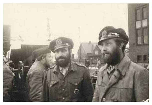 Two members of U 103 with a cap with a visor, the first (right) wears a leather jacket with double rows of buttons, without an upper pocket and normal lapels; the second wears a battle dress and wears the Iron Cross 1st Class. In the background a crew member in a leather jacket and bordmütze......................