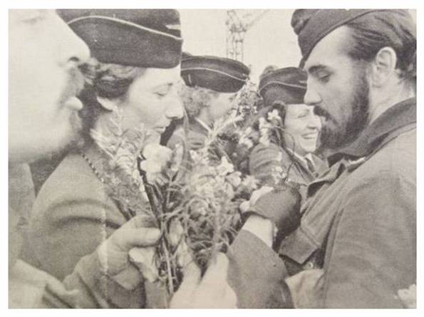 The ladies offer flowers to each crew member of the U-boat which has returned...........