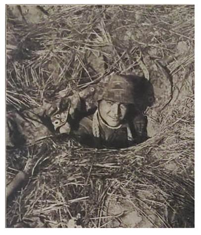 German grenadier in his foxhole, with the help of a tent tarpaulin he has camouflaged the position...........