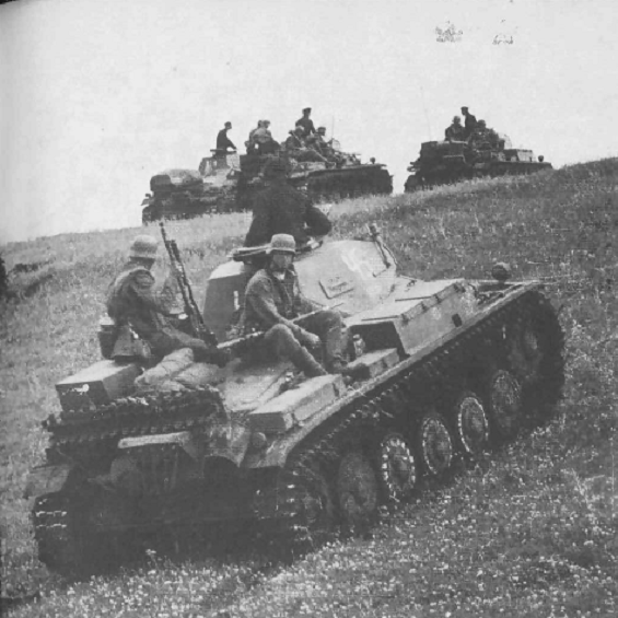 A German armored column with infantry riding on the tanks waiting for the order for jumping out; in the foreground a Pz Kw II.