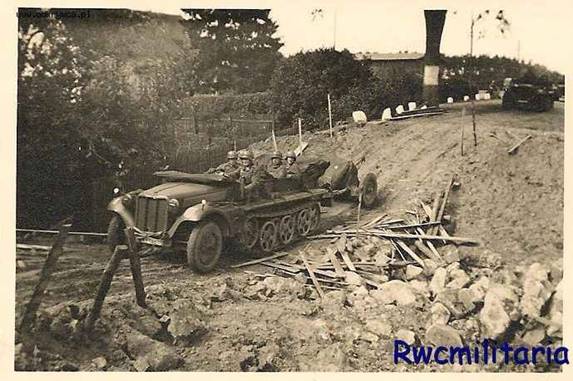 A Sd Kfz 10, towing an AA gun of 20 mm, crossing a gully on its way to the front ...............