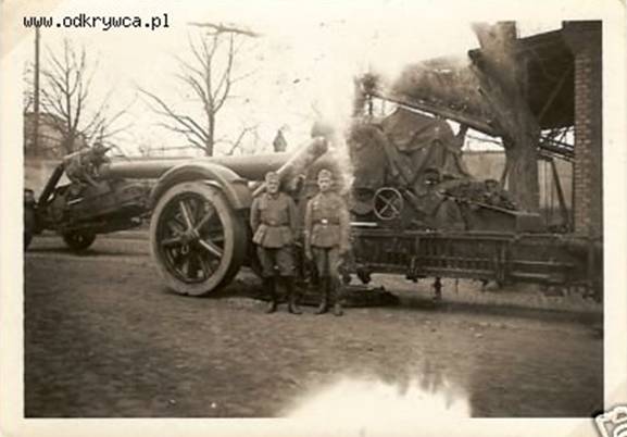 In the foreground the barrel of a 21 cm Mörser 18 and behind its carriage...............