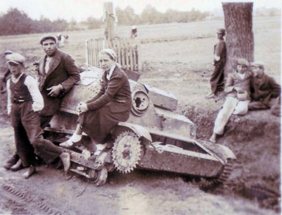 Polish civilians taking a rest, on and nearby, a disabled light tank by the roadside....................