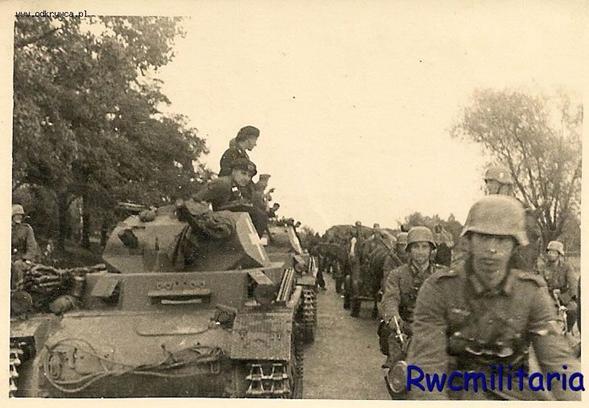 A Column of light tanks Pz Kw II being surpassed by cyclists and horse-drawn vehicles..................