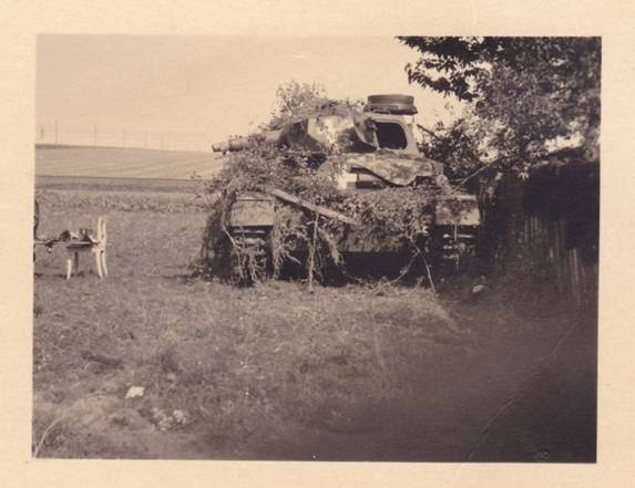 Close view of a Pz Kw IV camouflaged with foliage during a break in the march .........................
